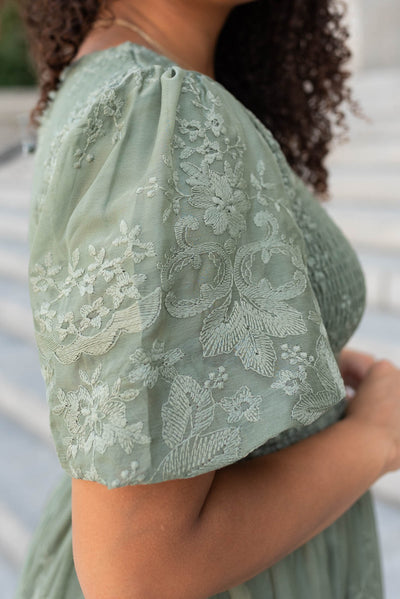 Close up of the sleeve and fabric of the deep sage embroidered dress