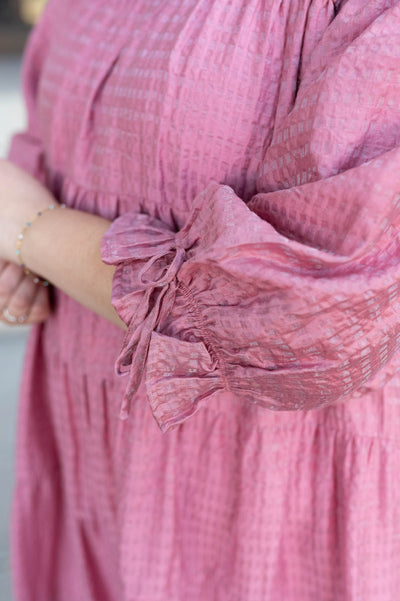 Close up of the fabric on the pink long sleeve dress with bow detail on the sleeves in plus size