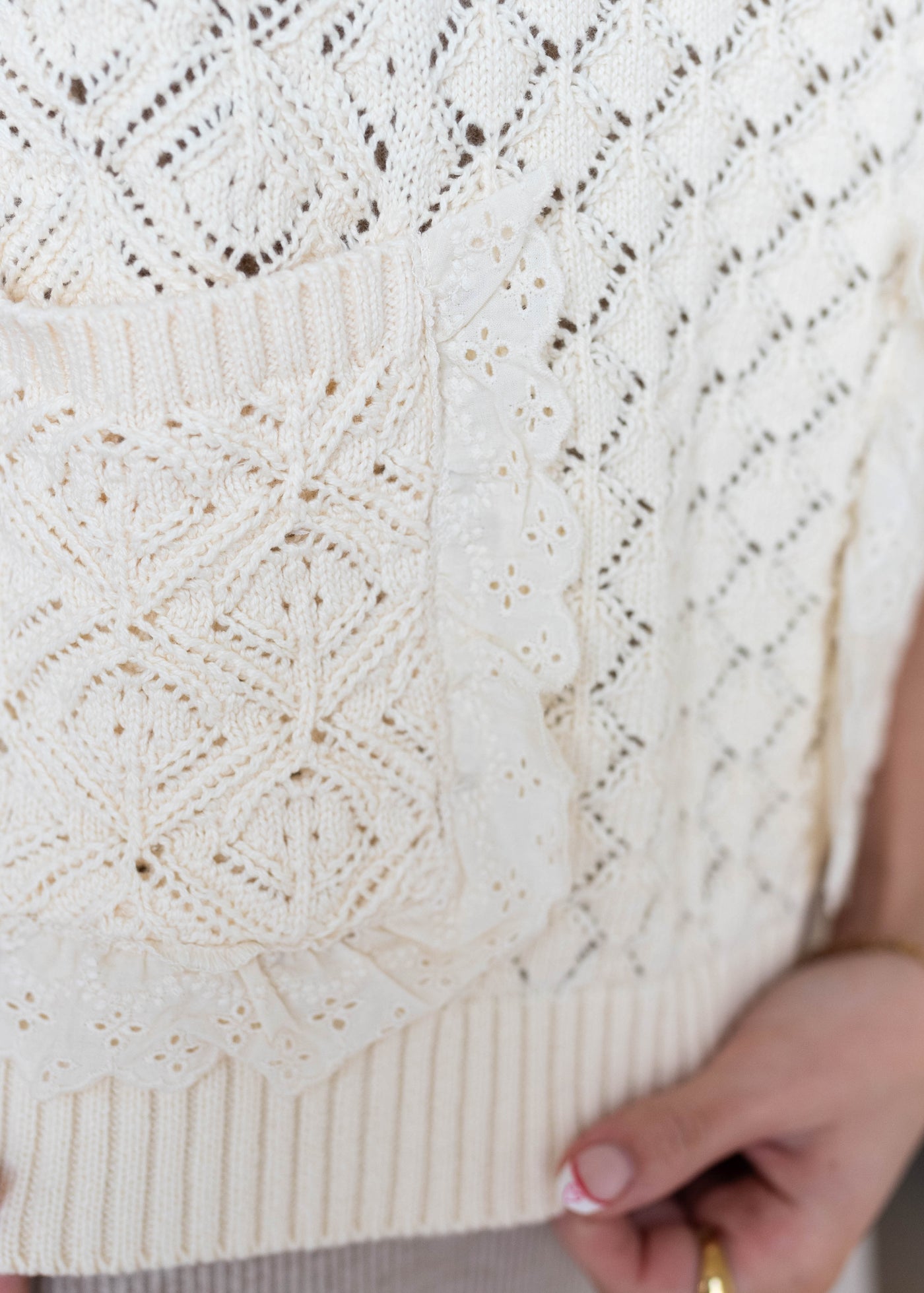 Close up of the knit pattern and lace around the pocket on the cream knit sweater vest