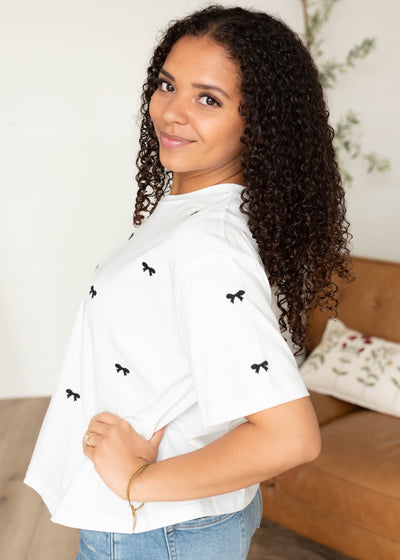 Side view of the white tee with black embroidered bow top