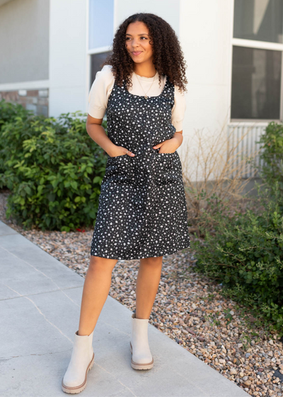 Front view of the black floral jumper dress with front pockets