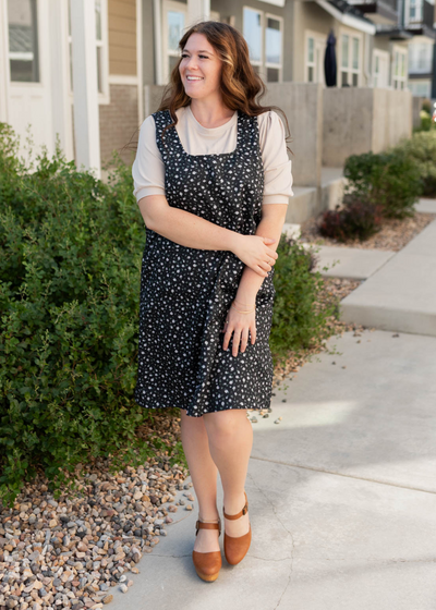 Front view of the black floral jumper dress with a square neck