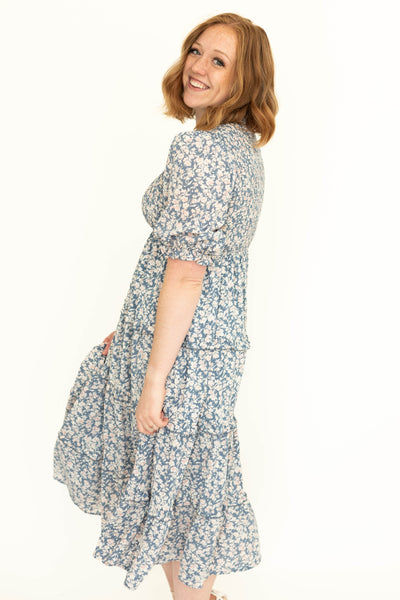 Side view of a short sleeve blue floral tiered dress.