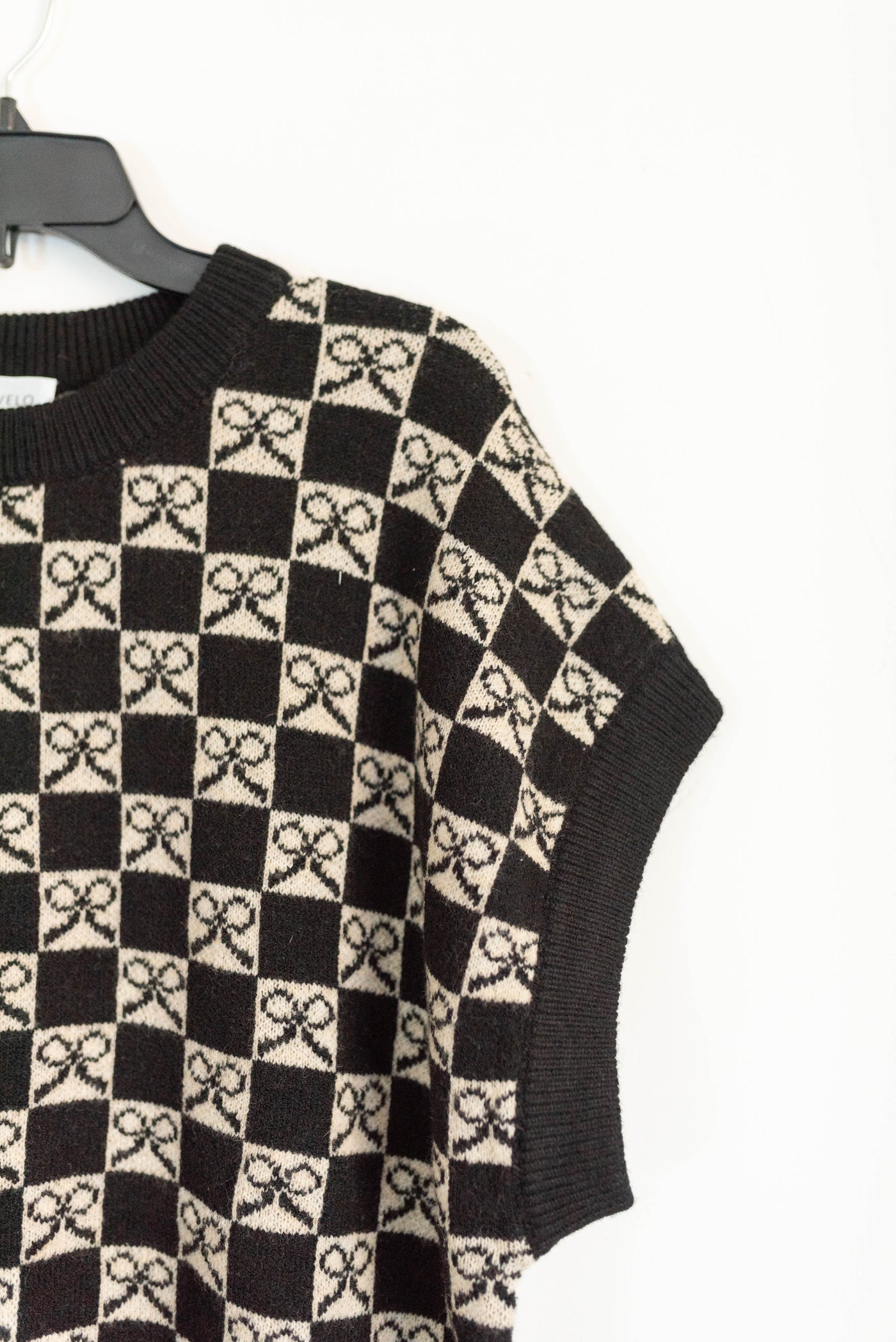 Close up of the print on the black checkered bow sweater vest