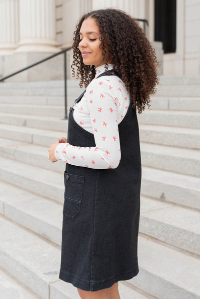 Side view of teh black denim overall dress