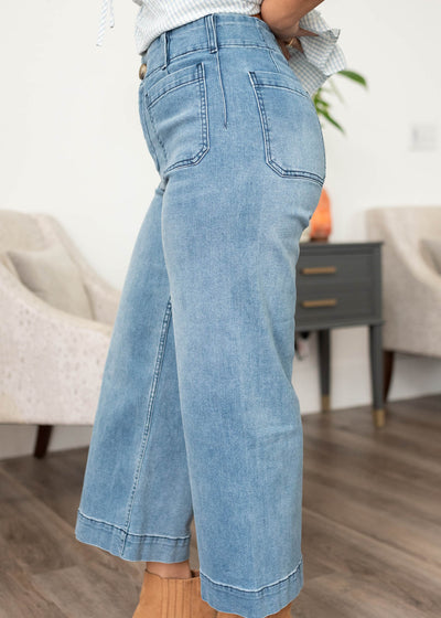 Side view of the dark denim pants with wide leg and front stitch pockets