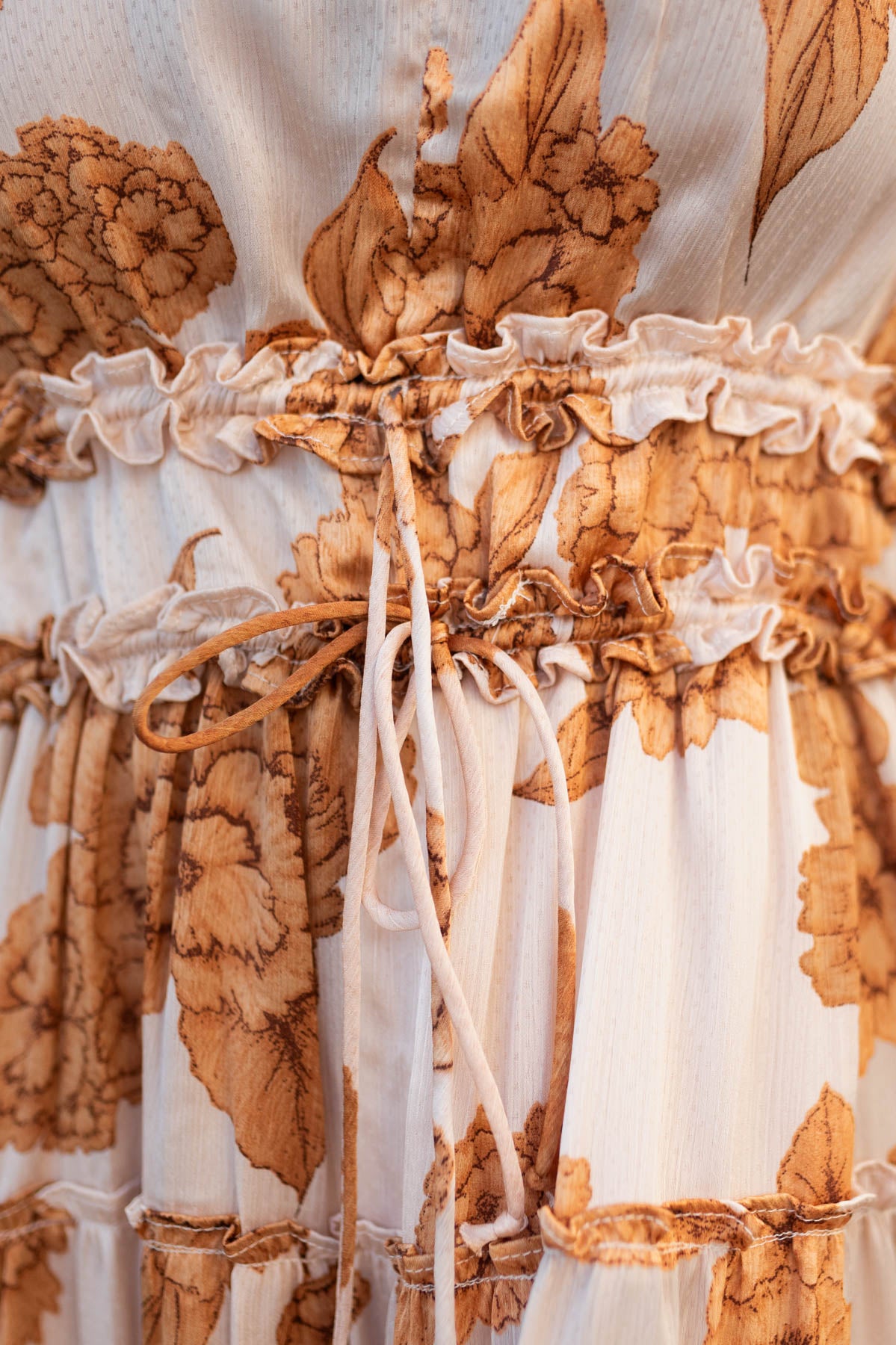 Close up of the waist ruffling on the beige floral dress