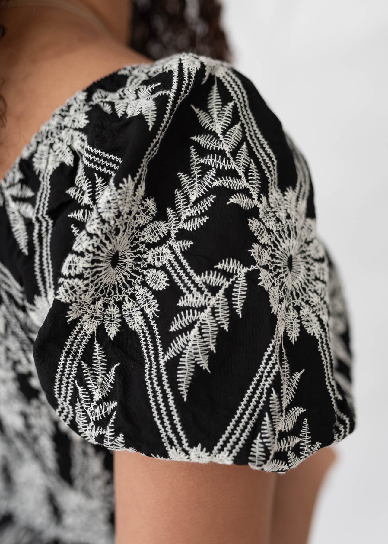 Close up of the sleeve and fabric on the black embroidered dress