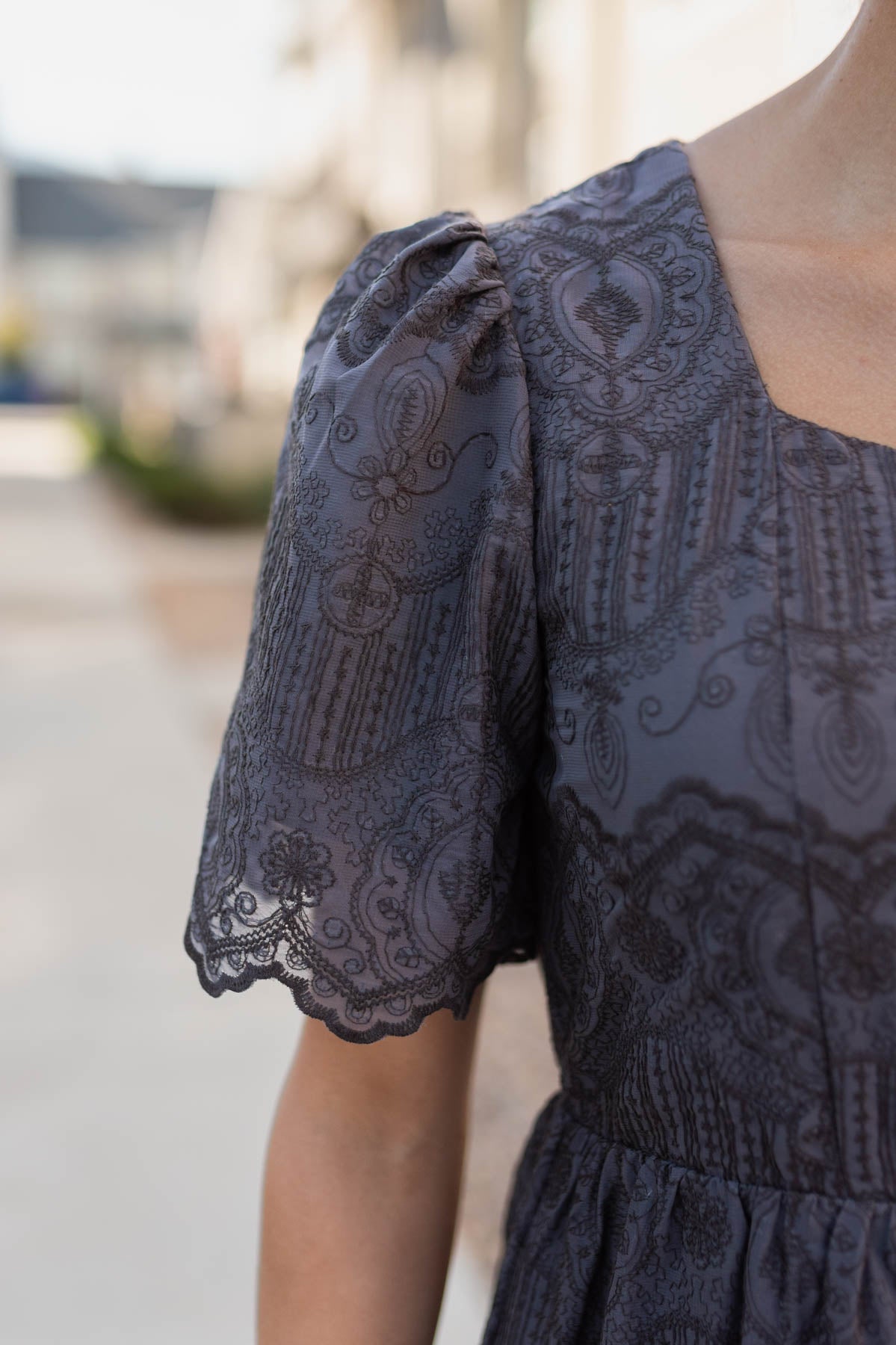 Close up of the fabric and sleeve on the charcoal embroidered dress