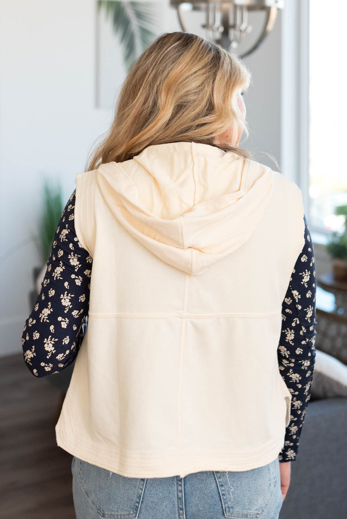 Back view of a cream vest with a hood