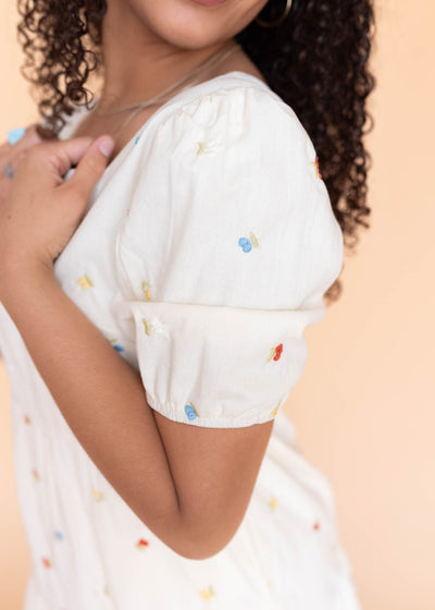 Close up of the sleeve and fabric on the cream floral embroidered dress