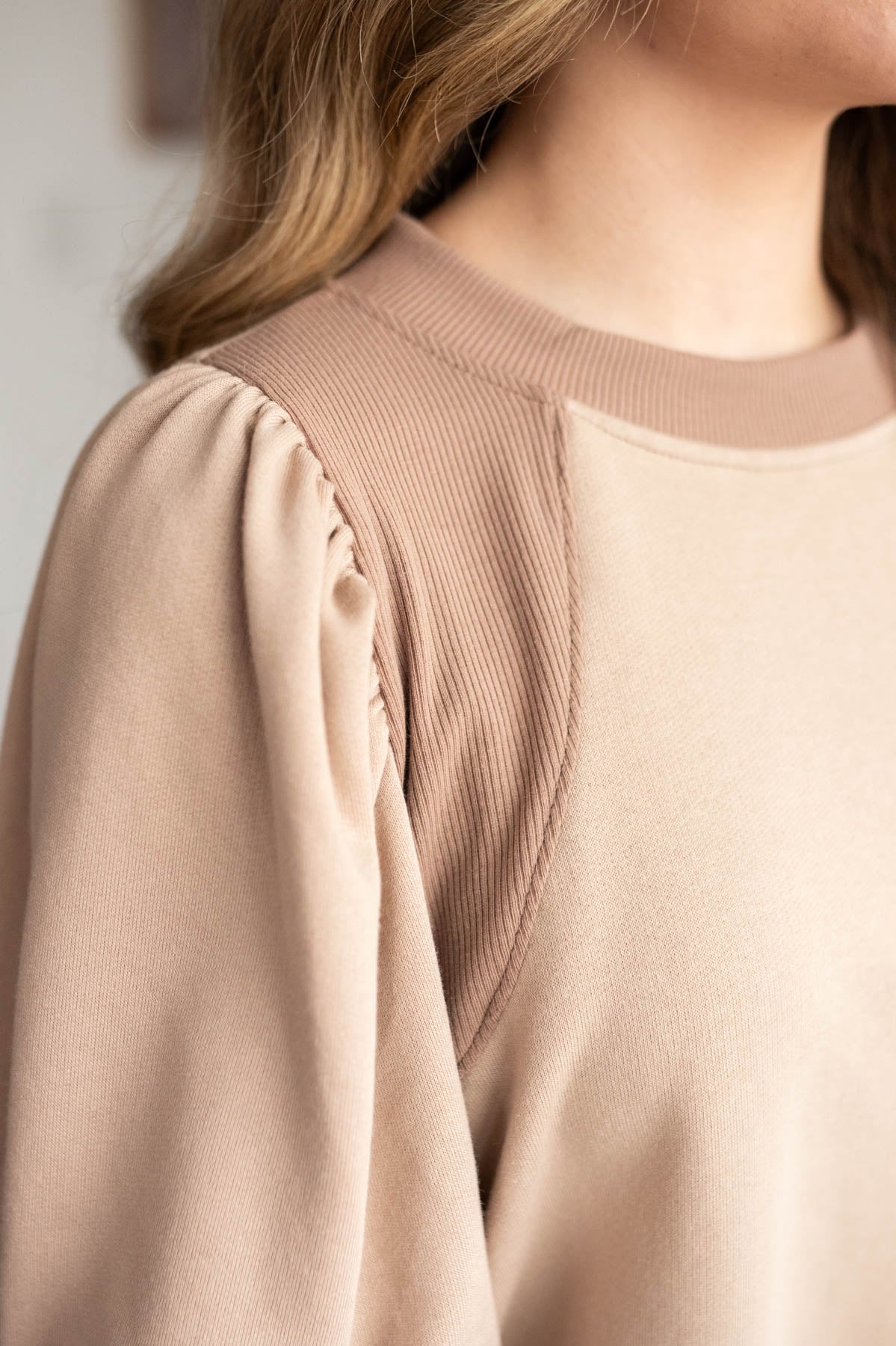 Close up of the sleeve and duel fabrics on the taupe puff sleeve pullover