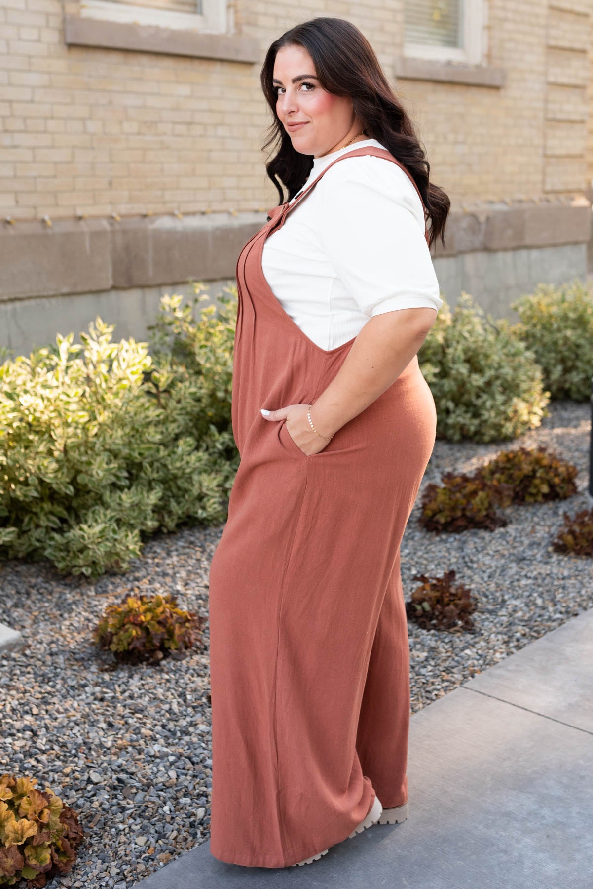 Side view of the rust wide leg overalls in plus size