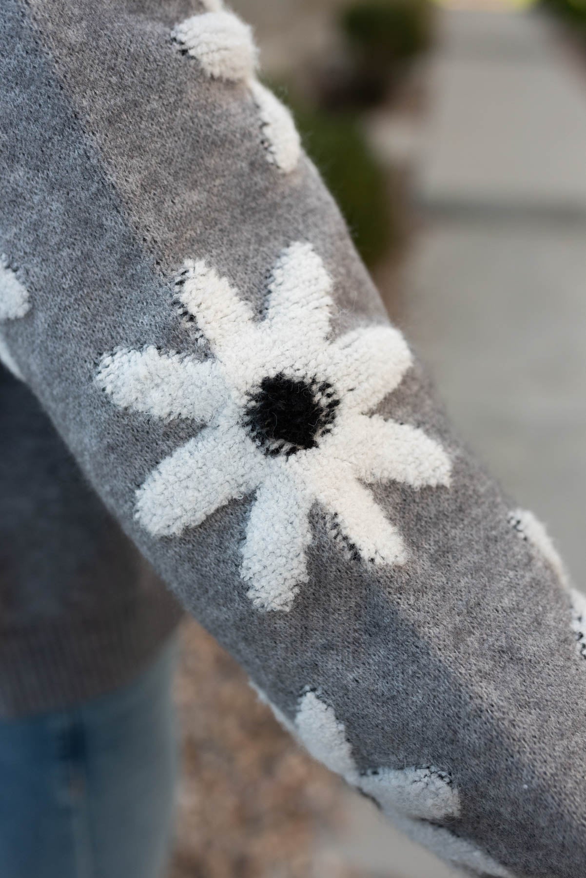 Close up of the white flower on the grey floral sweater