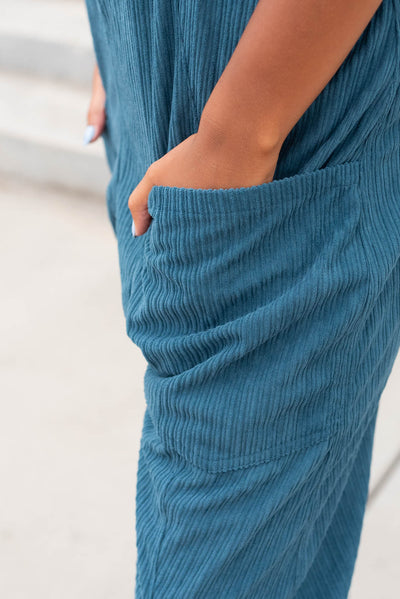 Close up of the pockets and fabric on the deep aqua corduroy overalls