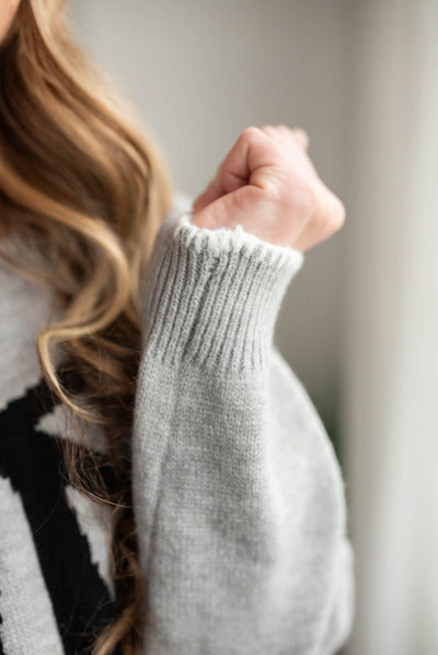 Close up of the white trim on the sleeve of the heather grey bow sweater