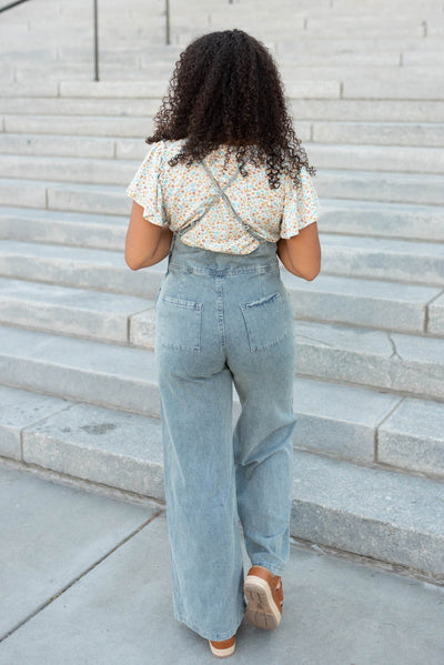 Back view of the blue denim jumpsuit with the criss cross back