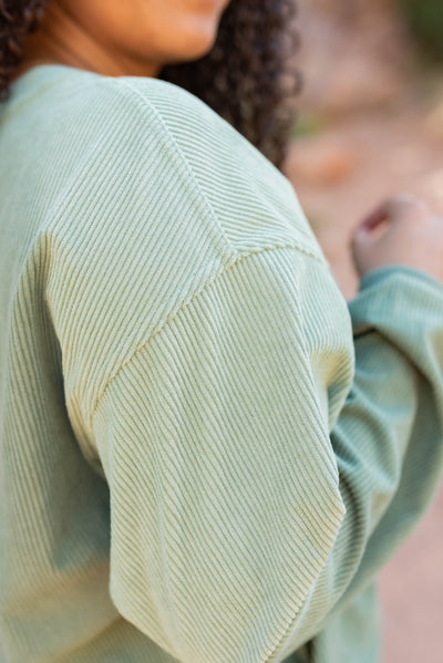 Close up of the fabric on the green ribbed sweatershirt