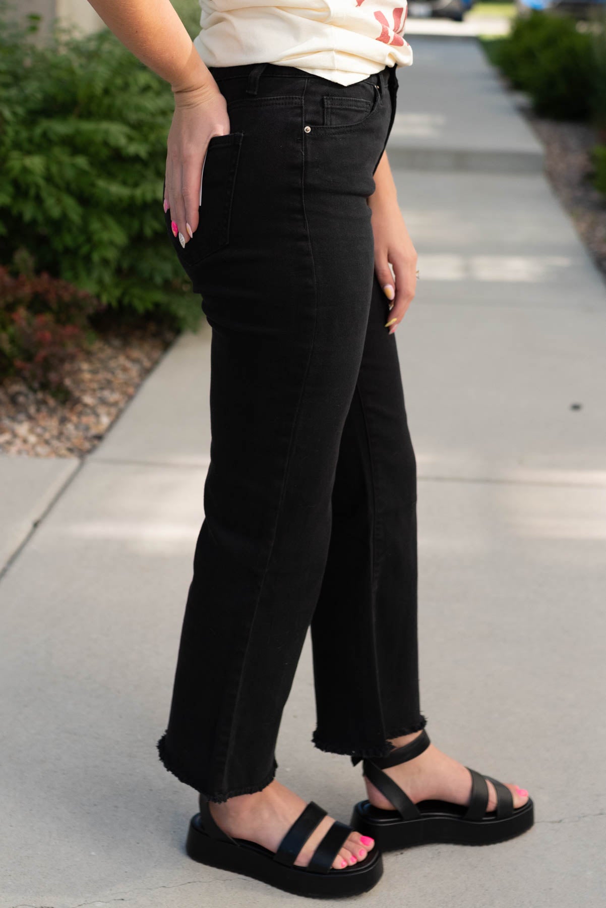 Side view of the black frayed bootcut pants