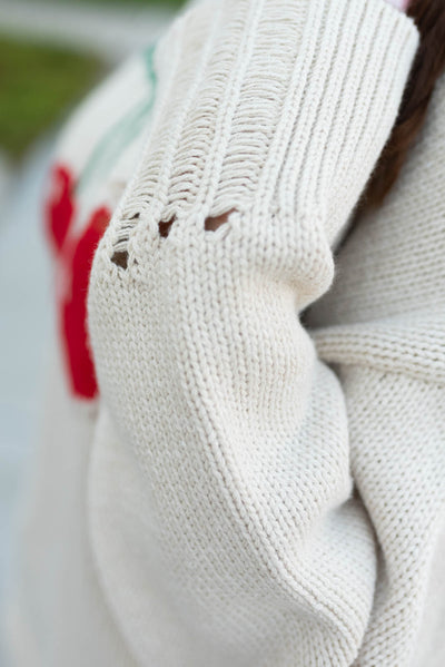 Close up of the distressing on the cuffs of the oatmeal cherry sweater