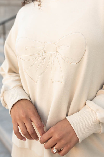 Close up of the bow on the beige embroidered bow pullover