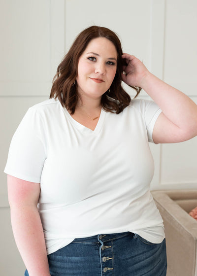 Plus size classic white v-neck top tucked into jeans